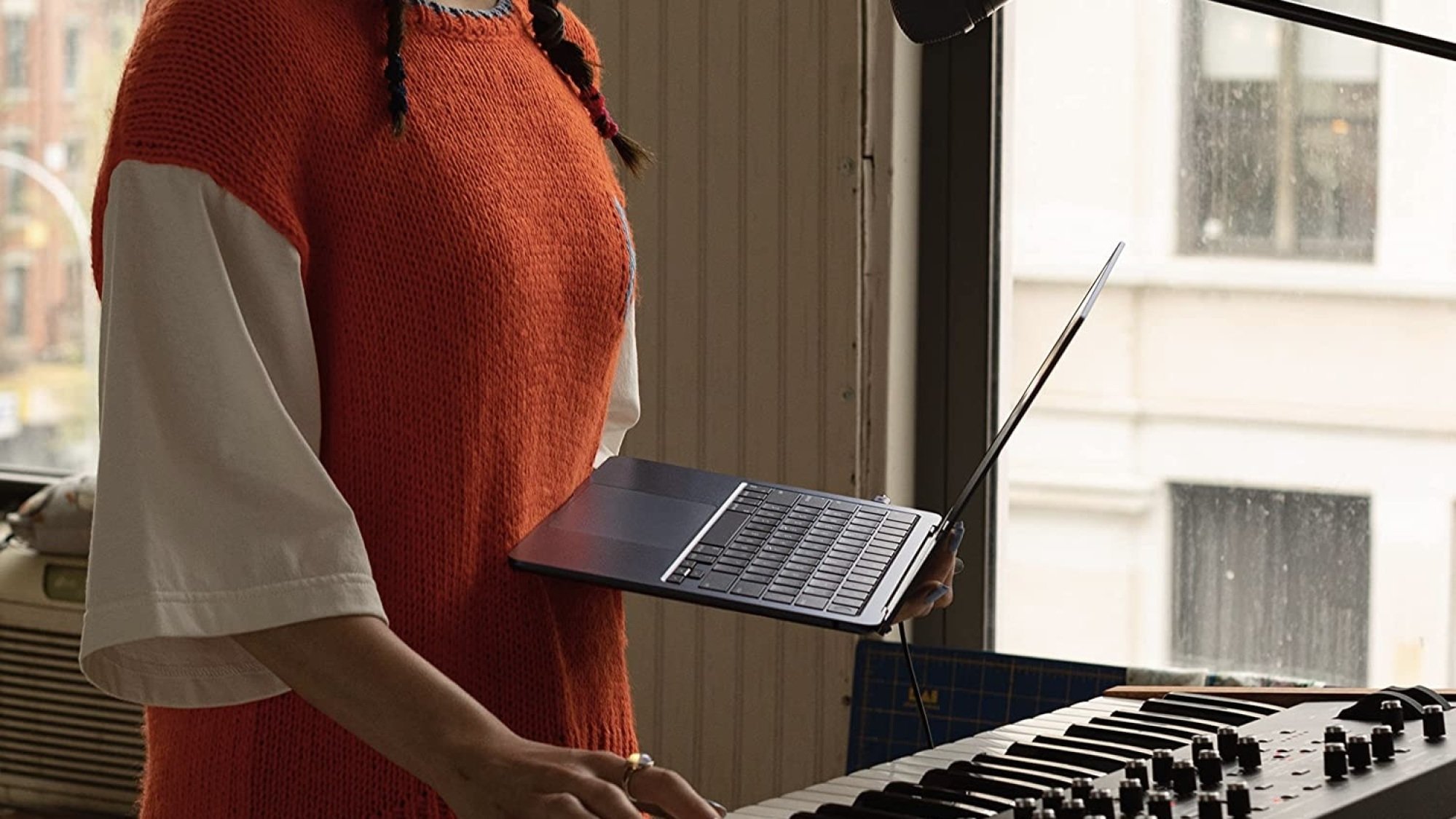 Orang yang memegang M2 MacBook Air di depan piano