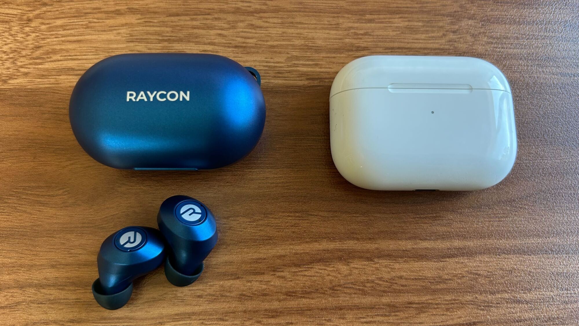 Kasing dan earbud earbud Raycon di sebelah kasus Airpods Pro Gen 1
