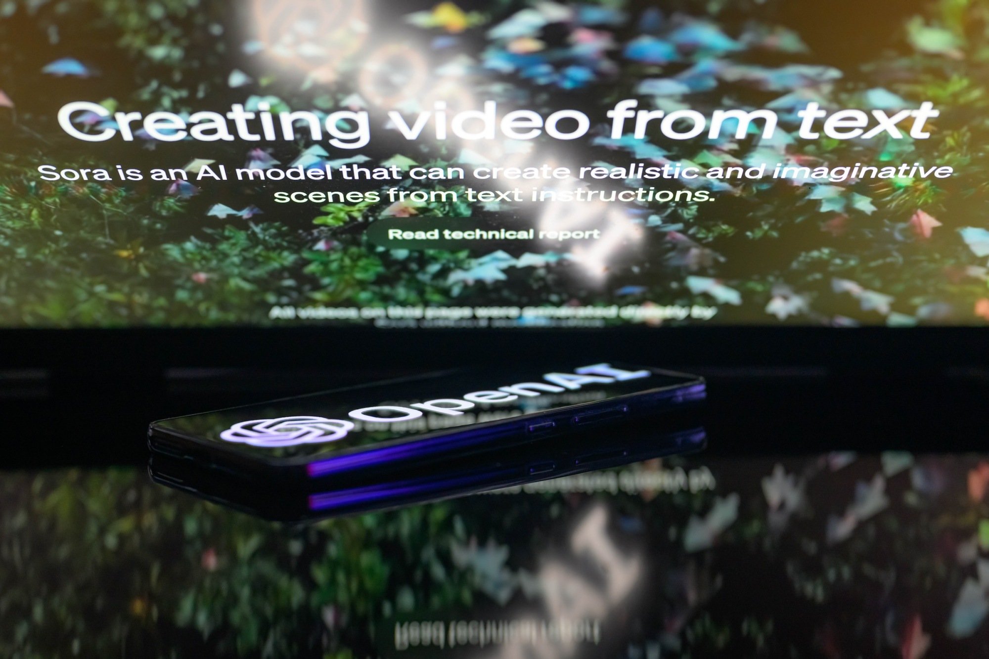 Logo OpenAI sedang ditampilkan pada smartphone dengan generator teks-ke-video Sora yang terlihat di latar belakang