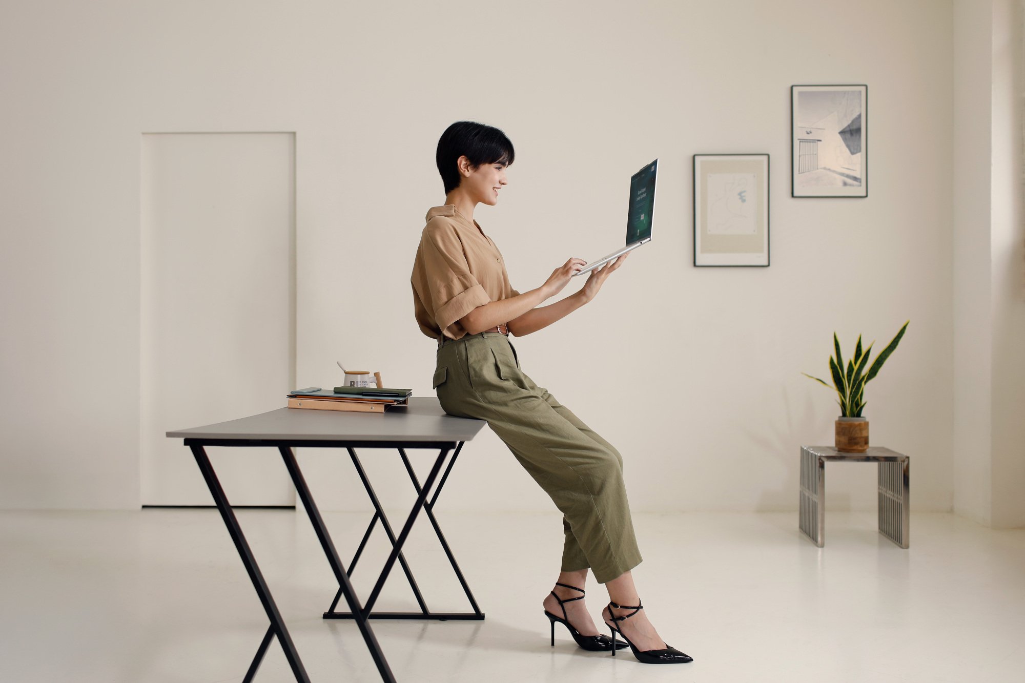Seorang wanita yang memegang Acer Swift Air 16 di ruang krem