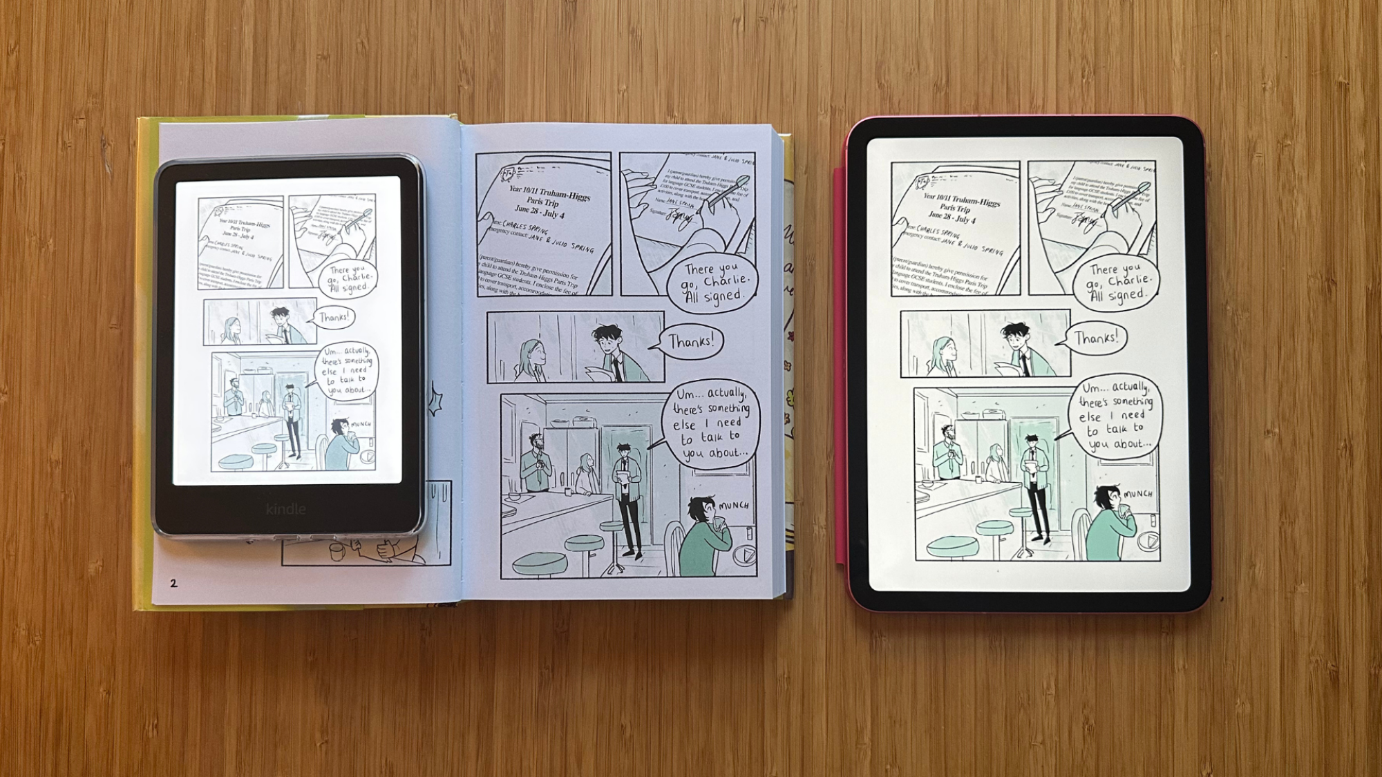 Kindle Colorsoft, HeartStopper Volume 3, dan iPad di sebelah satu sama lain di atas meja.
