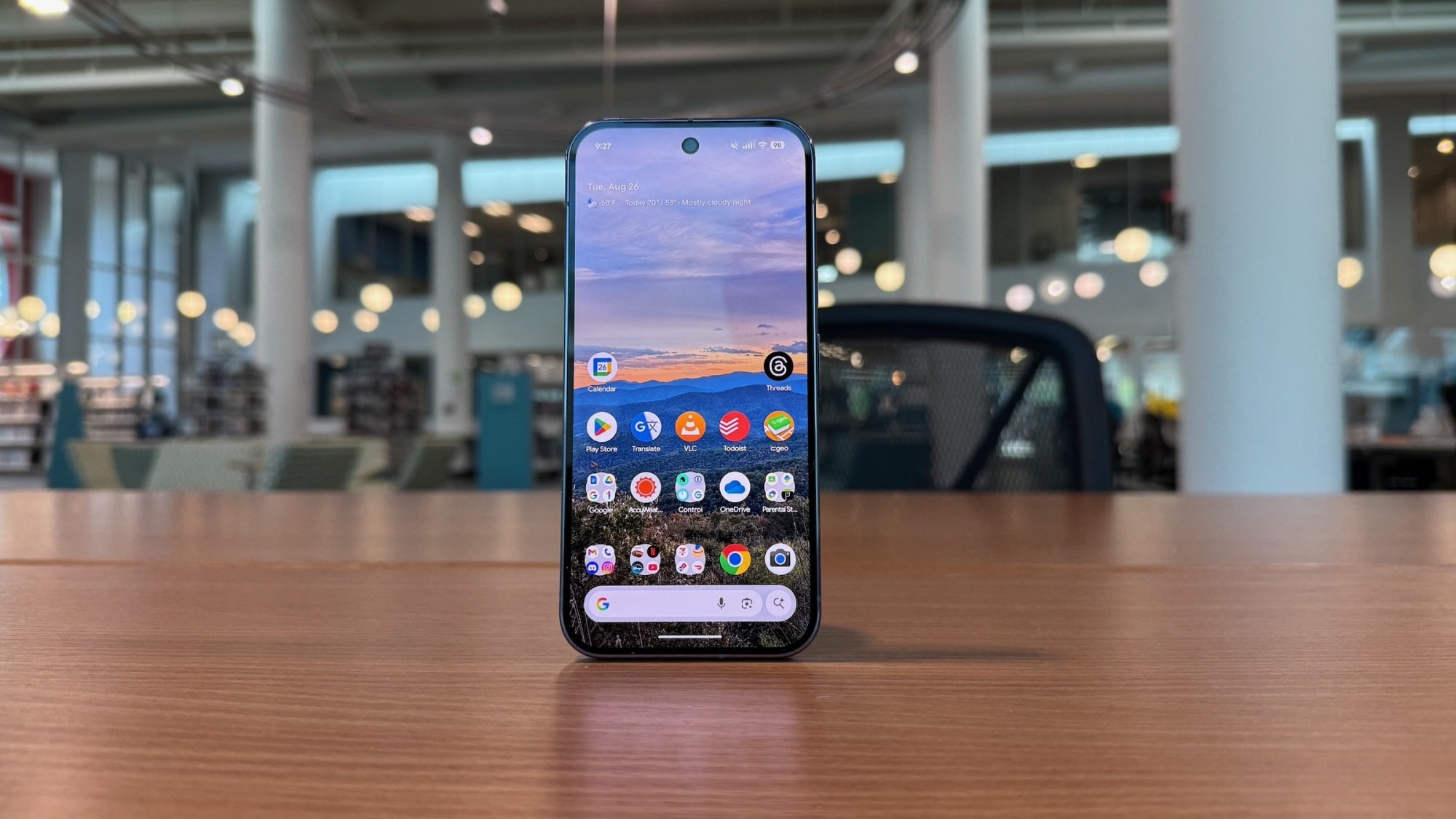 Pixel 10 Pro berdiri di atas meja yang menampilkan layar beranda dengan layar OLED