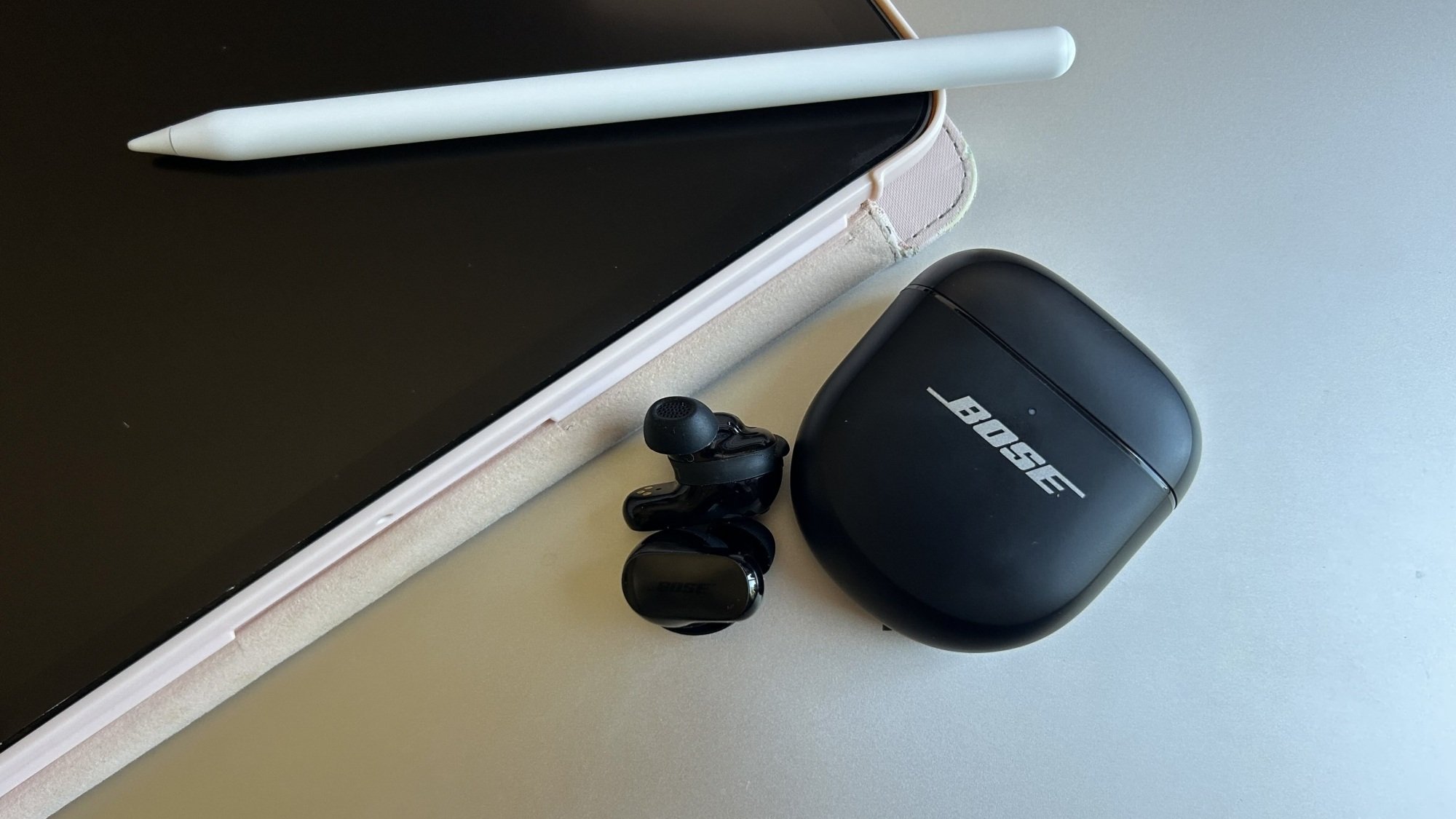 earbud bose di atas laptop dan di sebelah iPad
