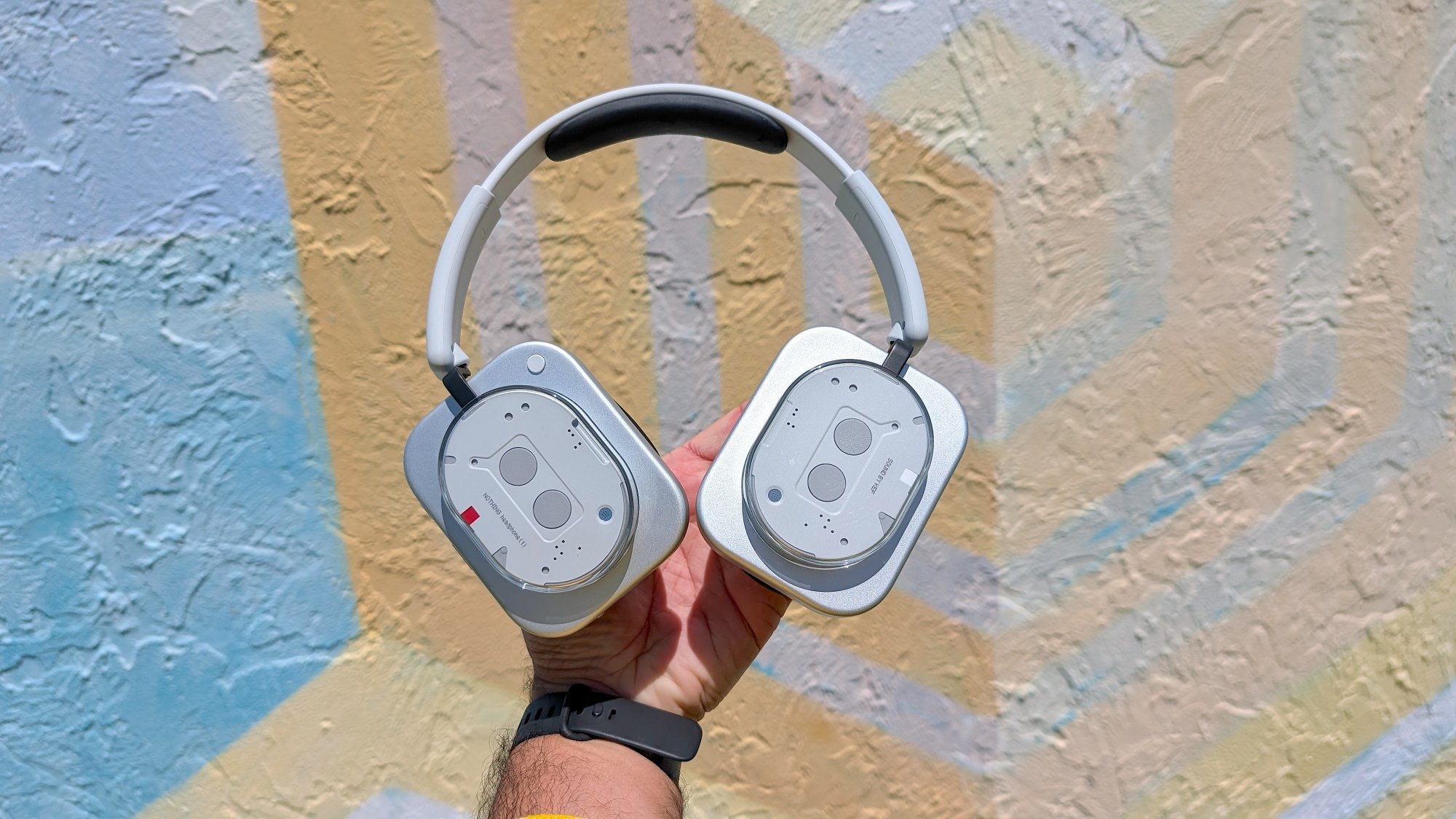 Tangan pria mengangkat sepasang headphone yang tidak ada di atas mural