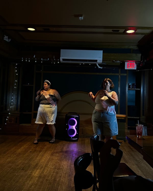 Dua orang di ruangan gelap melakukan karaoke.